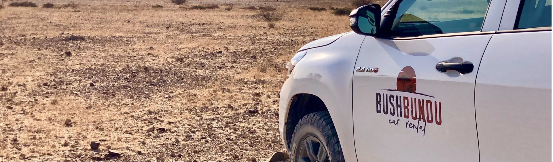 bushbundu-car-rental-windhoek-namibia-image-of-toyota-hilux-in-the-desert-with-bushbundu-logo